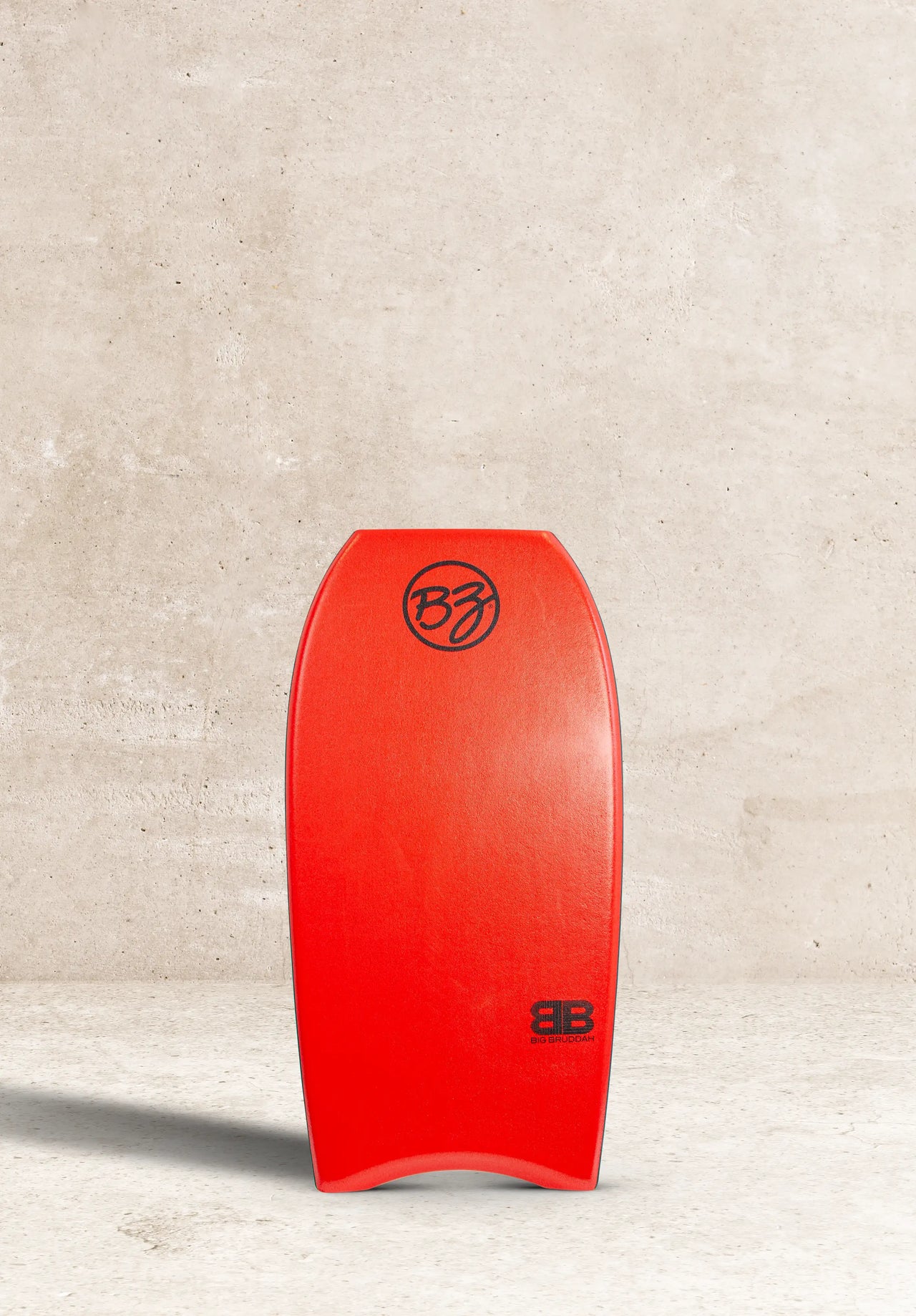 Vibrant red BZ Pro bodyboard with Big Bruddah logo, standing against concrete wall