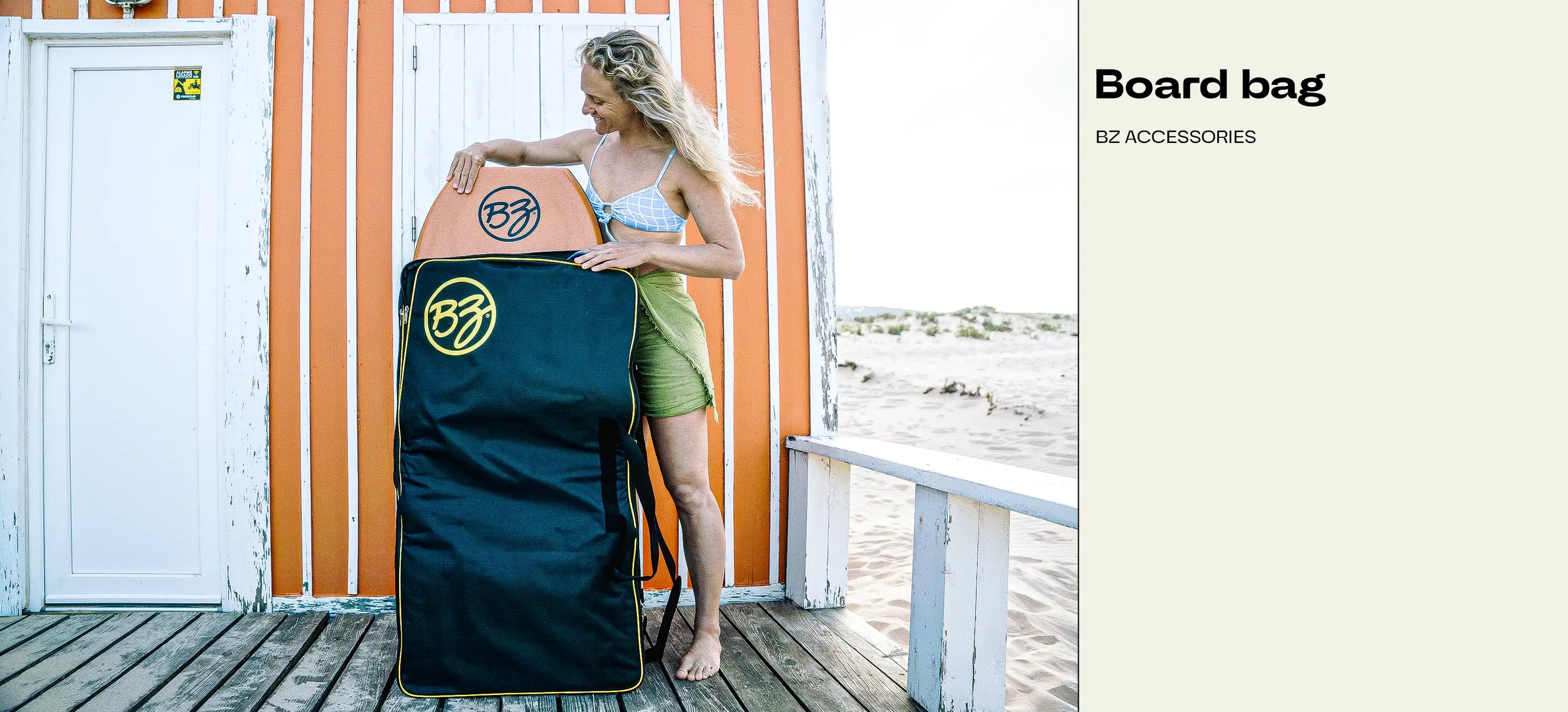 Woman holding BZ board bag with boogie board, standing on beach hut deck