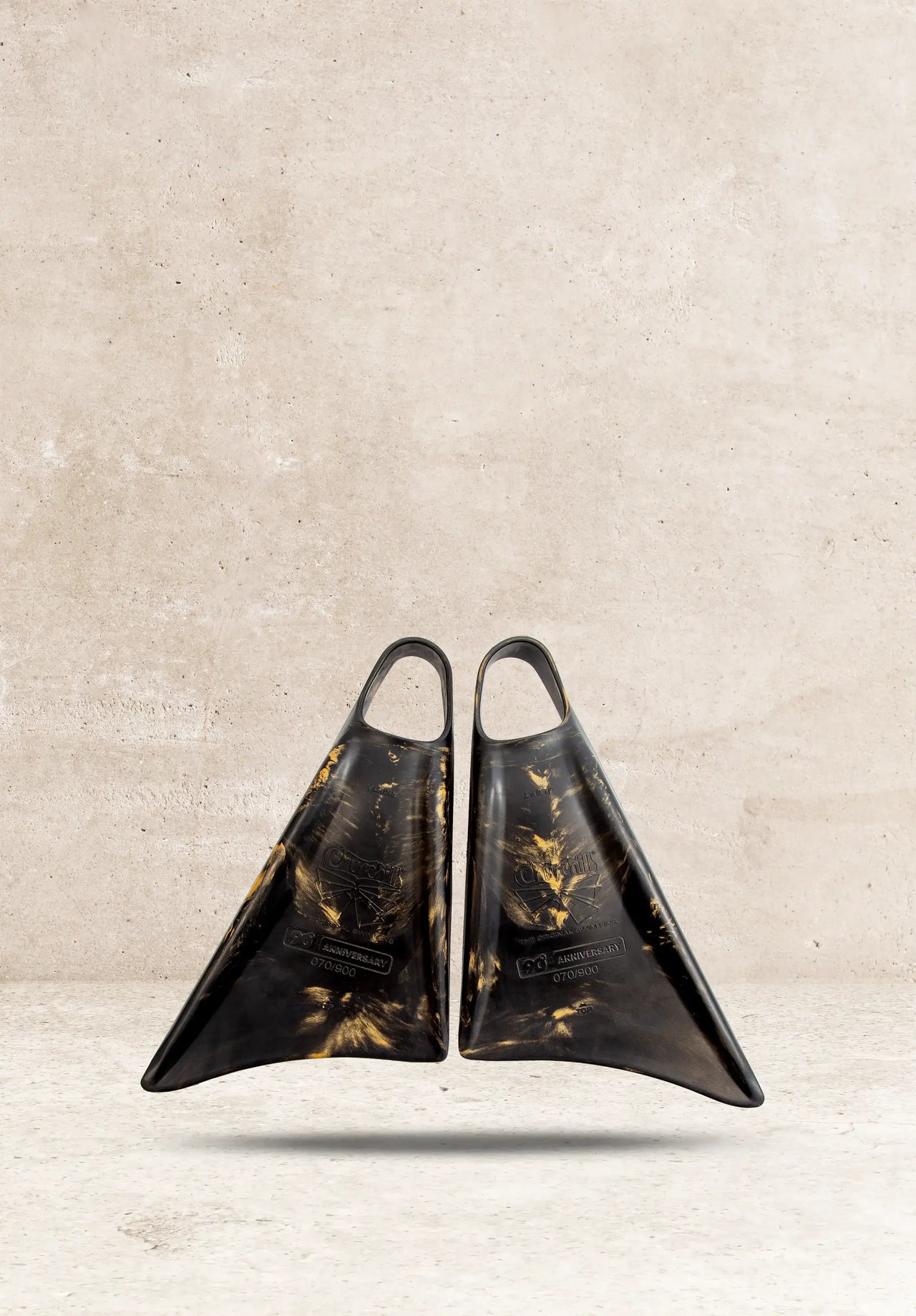 Black and gold Churchills 90th Anniversary swim fins, limited edition, against concrete background