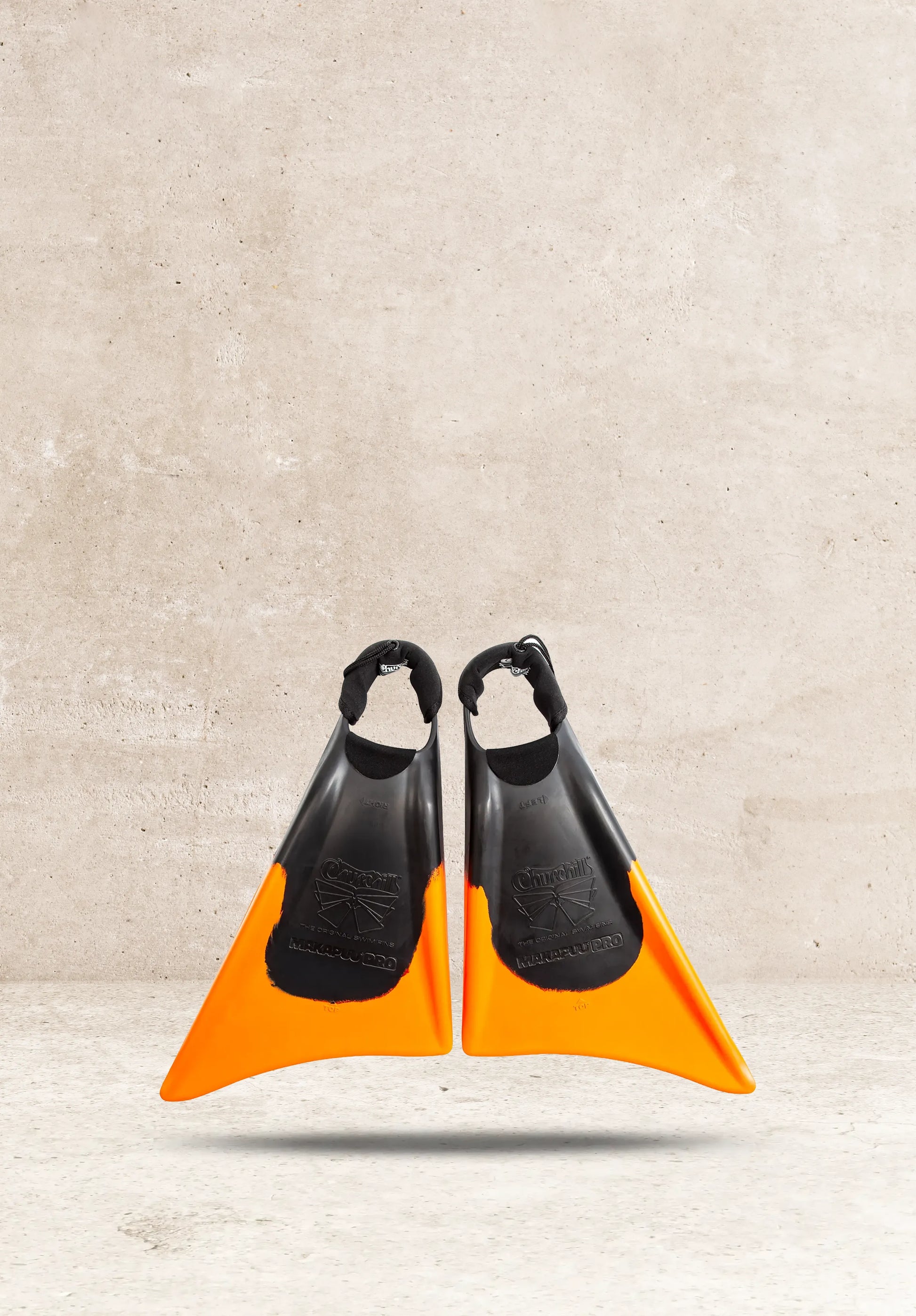 Churchill Makapuu Pro swim fins, black and orange, against concrete background