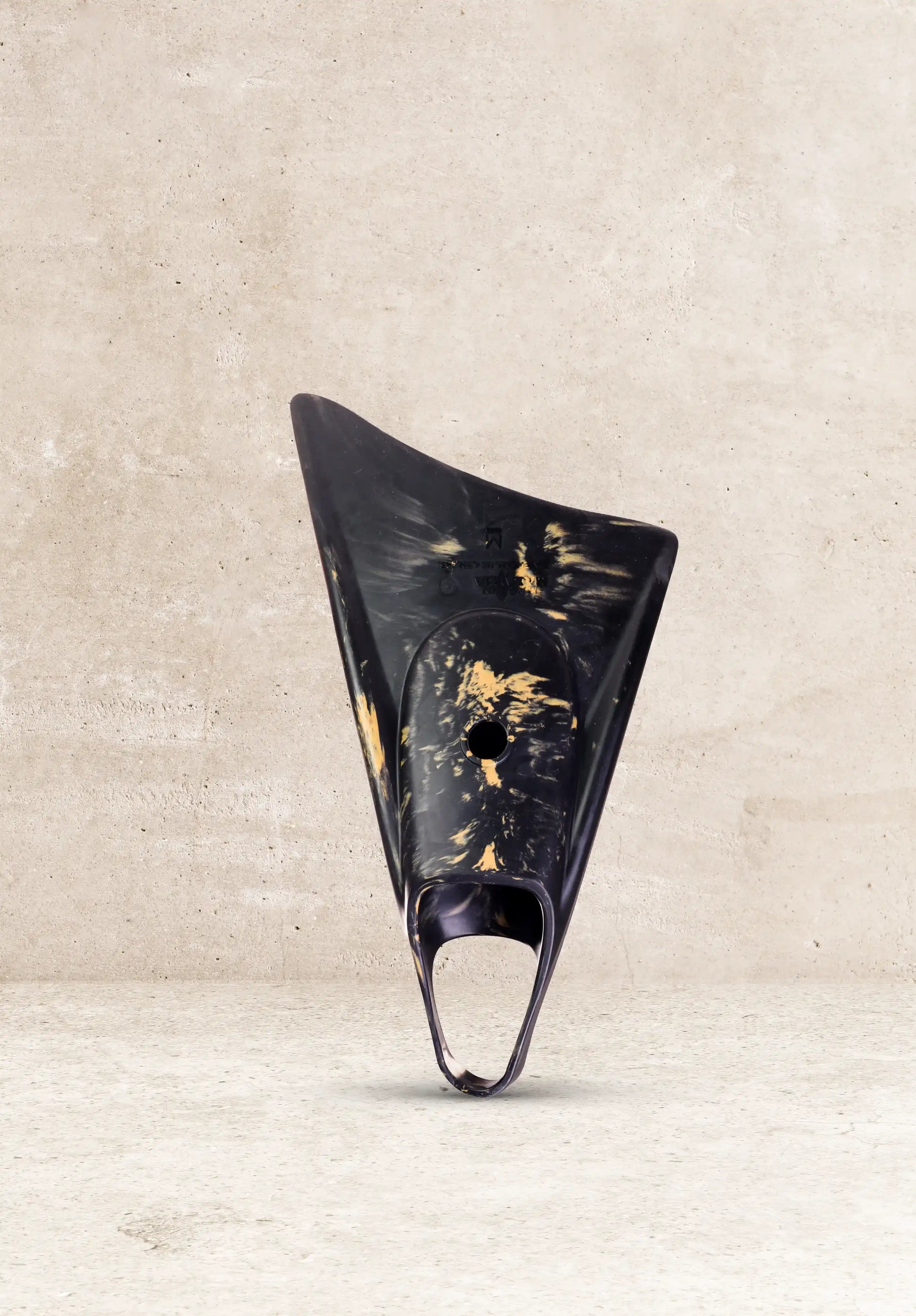 Black and gold boogie board fin against concrete background