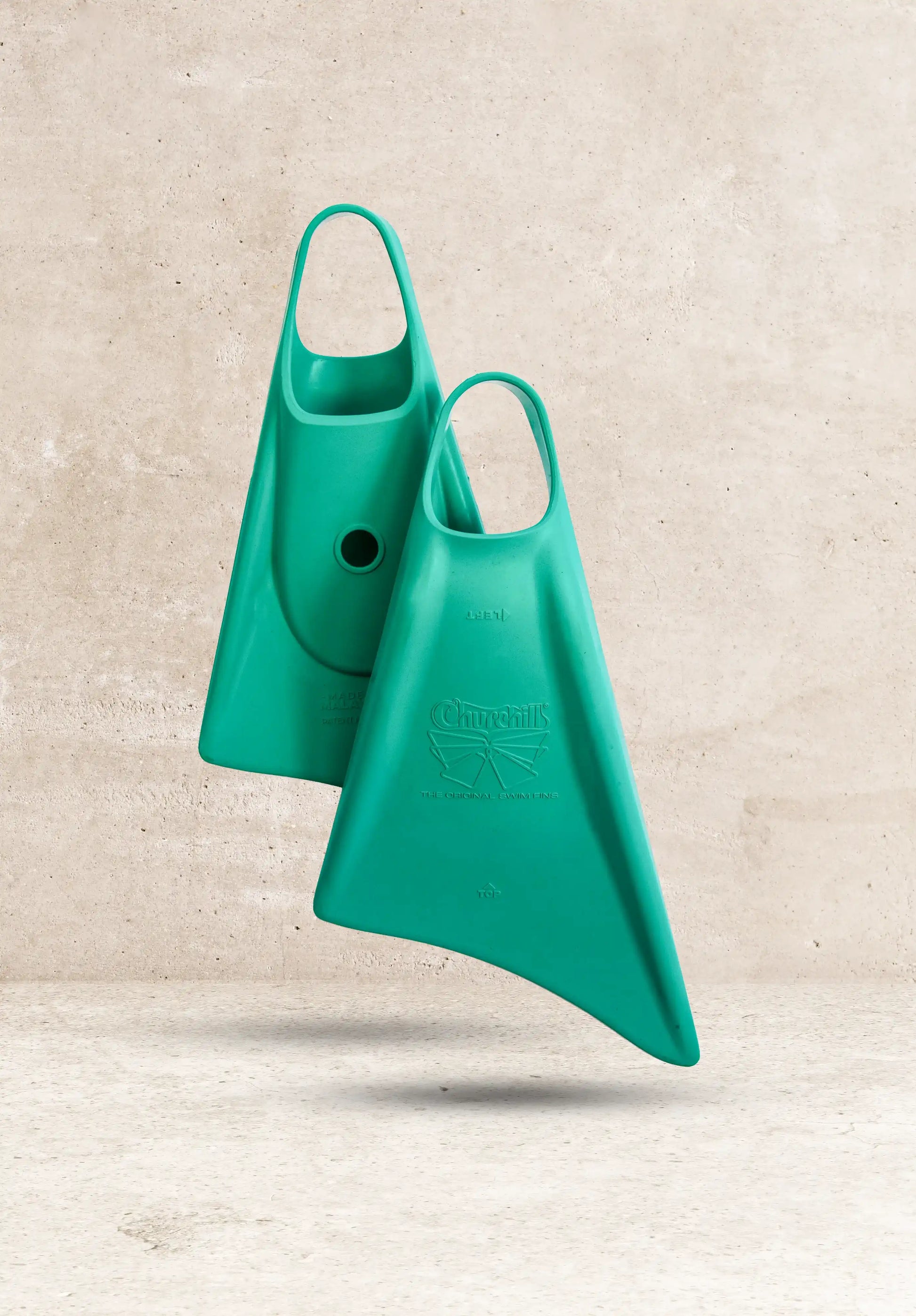 Teal Churchill's original swim fins against concrete background, classic design for swimming and training