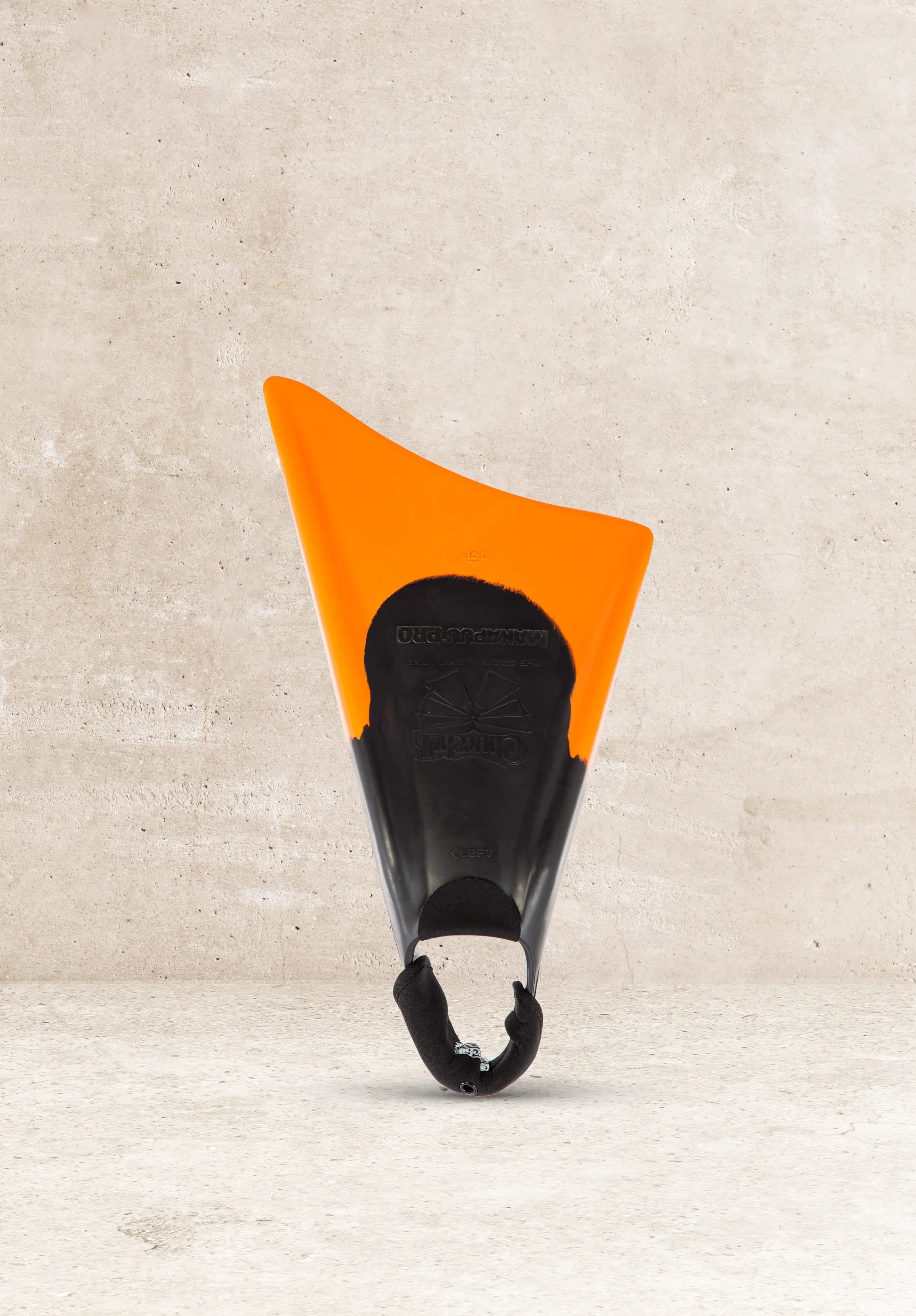 Orange and black Makapuu Pro swim fin for bodyboarding, featuring Current Designs branding against concrete background