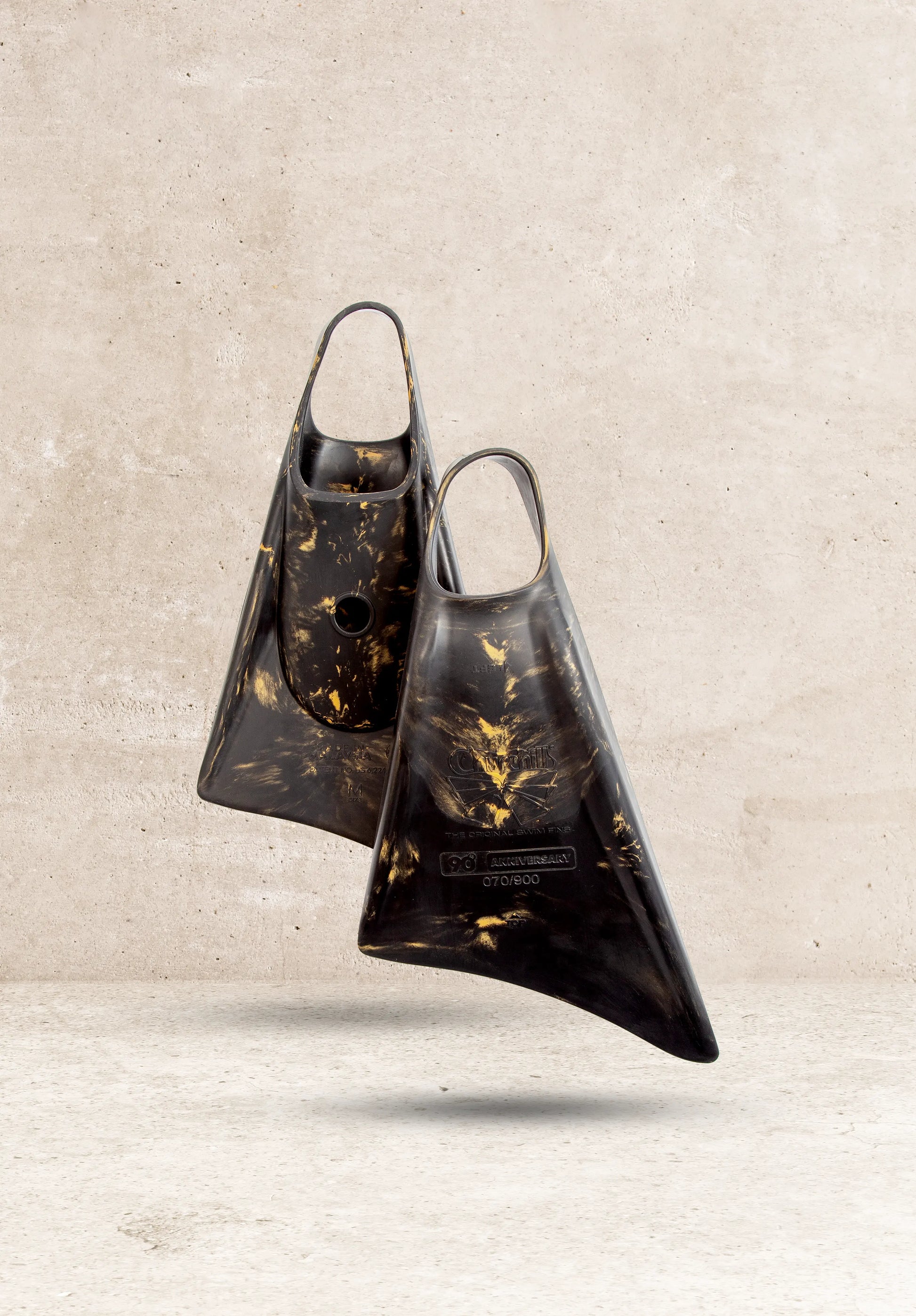 Black and gold Churchills 90th Anniversary swim fins, limited edition, against concrete background