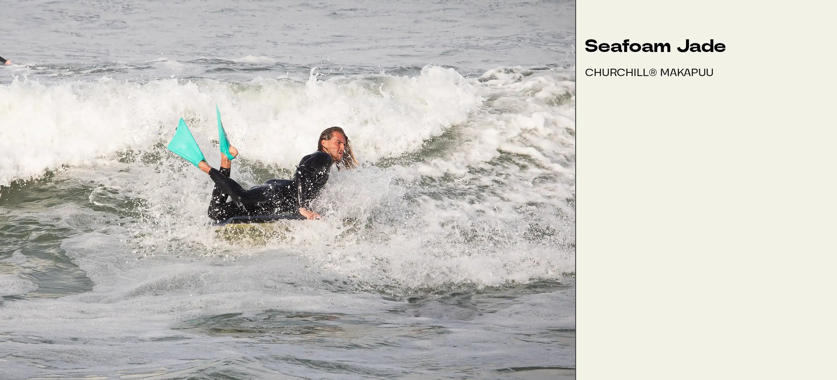 Surfer riding wave on Seafoam Jade Churchill Makapuu board with teal fins, wearing black wetsuit